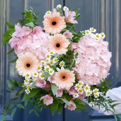 Ramo variado de flores em tons lilás, pêssego e branco com folhas verdes