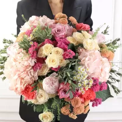 Bouquet colorido de flores variadas segurado por pessoa com blazer preto