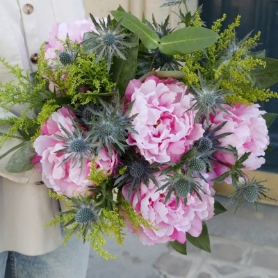 Ramo de peónias cor-de-rosa com folhas verdes e flores amarelas e azuis