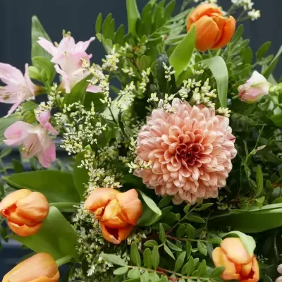 Bouquet de flores com tulipas laranja, flor central pêssego e folhas verdes