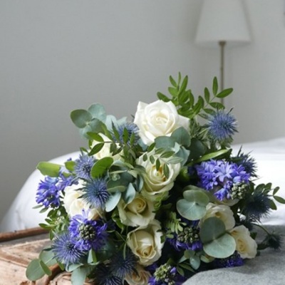 Ramo de flores brancas e azuis sobre mala de madeira em quarto.