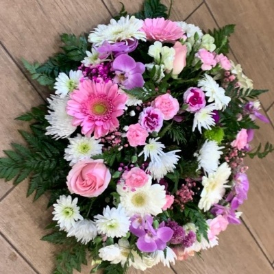 Arranjo floral redondo com flores naturais coloridas sobre piso de madeira clara