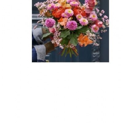 Bouquet colorido de flores variadas segurado por uma pessoa com luvas e casaco azul