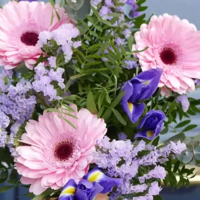 Arranjo floral com flores rosa, lilás e roxas com folhas verdes