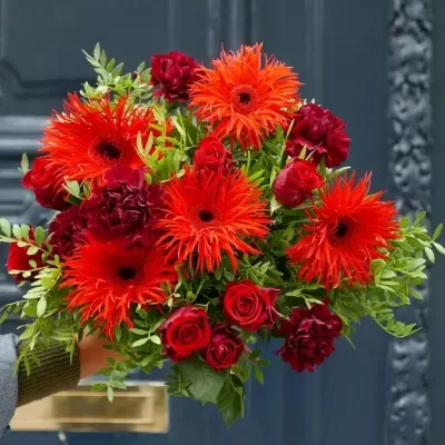 Bouquet colorido de flores vermelhas e laranja com folhagem verde