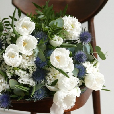 Bouquet de flores branco e azul sobre banco de madeira escura