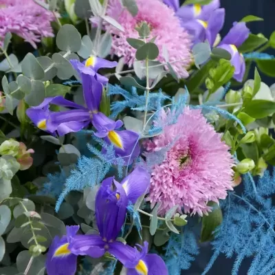 Arranjo floral com flores roxas, rosas e folhas verdes e azuladas