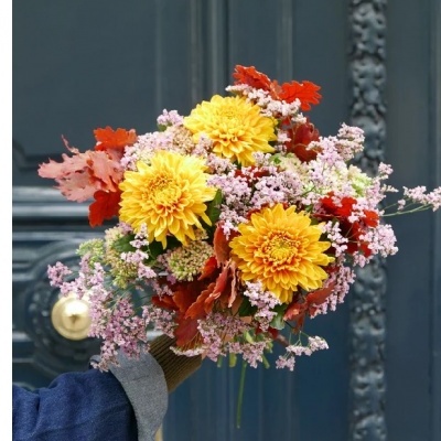 Ramo de flores coloridas com crisântemos amarelos e folhas vermelhas sobre fundo de porta azul