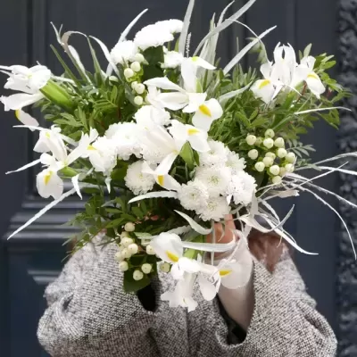 Bouquet grande de flores brancas com verde e ramos prateados, segurado por pessoa em casaco cinzento