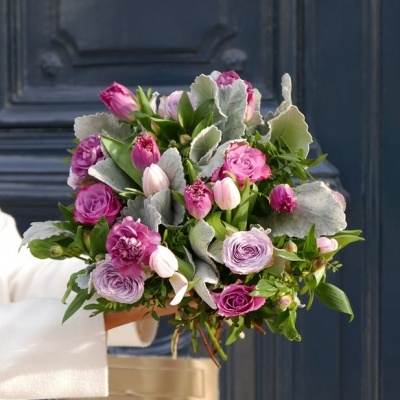 Ramo de flores com rosas e tulipas com folhagem a frente de uma porta azul escura
