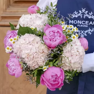 Buquê de peônias cor-de-rosa e flores brancas com folhagem verde, pessoa com avental azul MONCEAU FLEURS