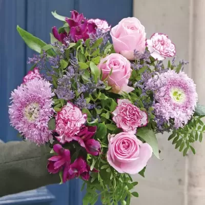 Bouquet de flores rosas, lilases e verdes com fundo azul e bege