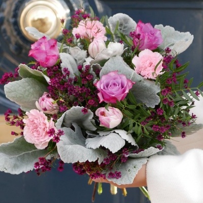 Bouquet rosa e roxo com folhas acinzentadas em fundo azul e dourado