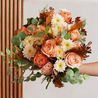 Ramo de flores com rosas pêssego, crisântemos brancos e folhas verdes em fundo claro