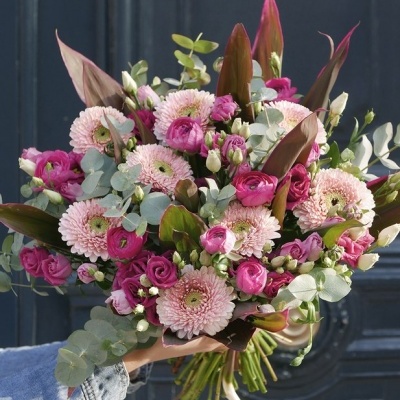 Buquê colorido de flores rosas e verdes com folhas castanhas numa mão