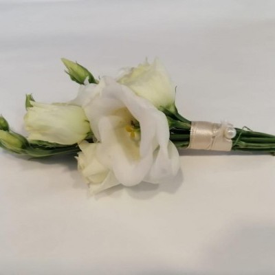 Bouquet pequeno de flores brancas com caules verdes envoltos em fita branca com pérolas