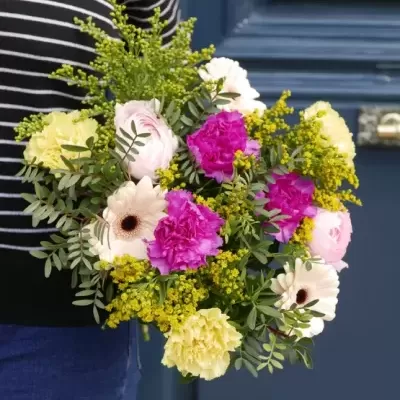 Buquê colorido de flores segurado em frente a porta azul