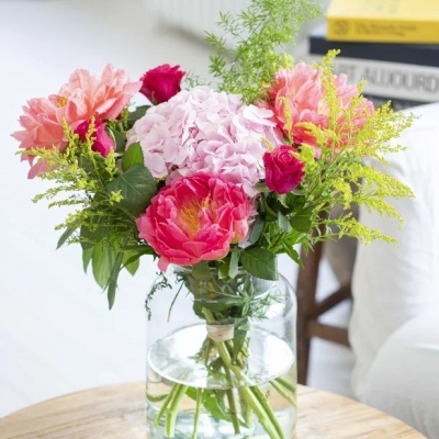 Arranjo de flores coloridas num vaso de vidro sobre mesa de madeira