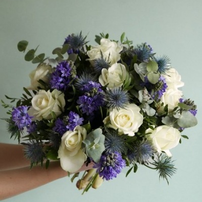 Buquê de flores brancas e roxas com folhagem verde em fundo verde claro