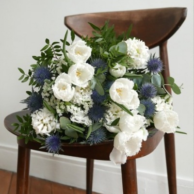 Ramo de flores brancas e azuis numa cadeira de madeira escura