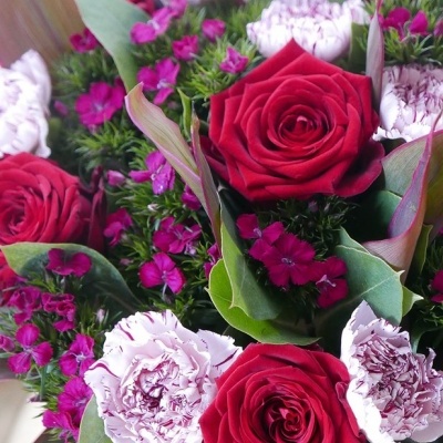 Buquê de flores com rosas vermelhas, cravos brancos e pequenas flores roxas
