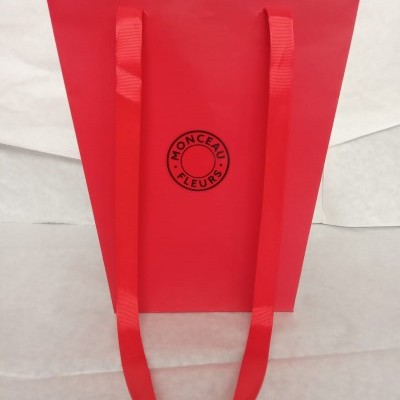Saco de papel vermelho com alças vermelhas e texto preto MONCEAU FLEURS