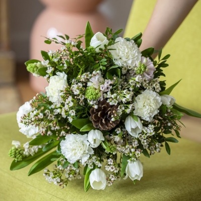 Ramo de flores brancas e verdes com pinheiro colocado sobre tecido verde limão