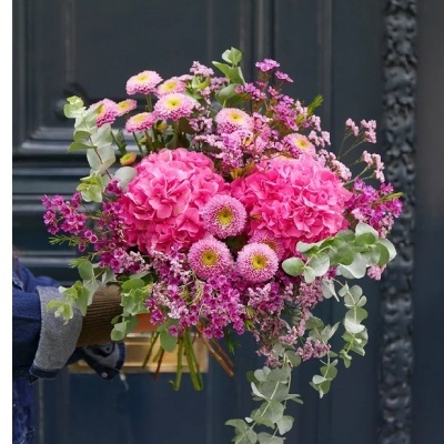 Buquê de flores rosas e folhagem verde contra porta escura