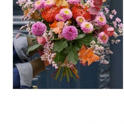 Buquê colorido de flores segurado por mão com luva