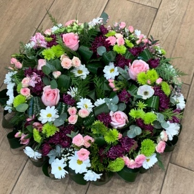 Arranjo floral colorido redondo com rosas cor-de-rosa e folhas verdes