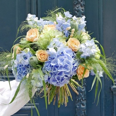 Bouquet de flores azuis, pêssego e verdes em porta azul