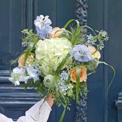 Buquê colorido de flores segurado em frente a porta azul