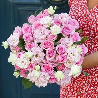 Buquê de flores rosa e branco segurado por pessoa com vestido vermelho floral em frente a porta azul
