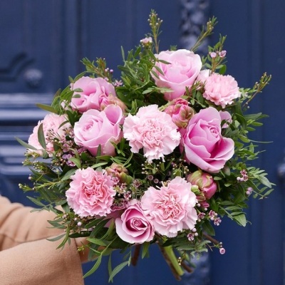 Buquê de rosas e cravos cor de rosa com folhagem verde e pequenas flores lilases