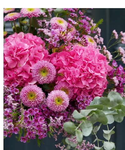 Arranjo floral com flores cor-de-rosa, lilás e folhas verdes
