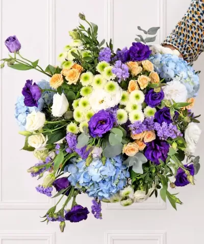 Arranjo floral colorido com rosas, flores roxas, lilases, crisântemos e hortênsias azuis