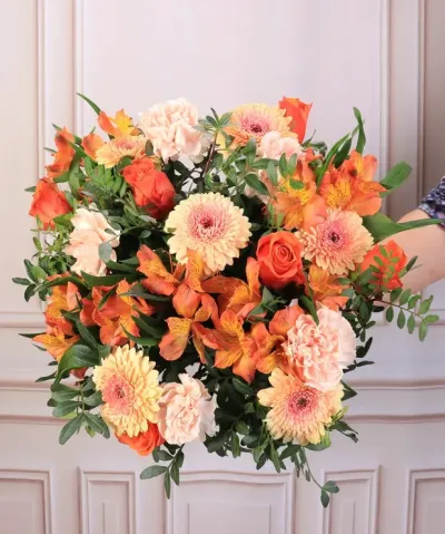 Bouquet colorido de flores laranja e cor de pêssego com folhas verdes