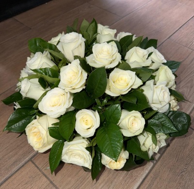 Bouquet de rosas brancas e folhas verdes sobre chão de madeira