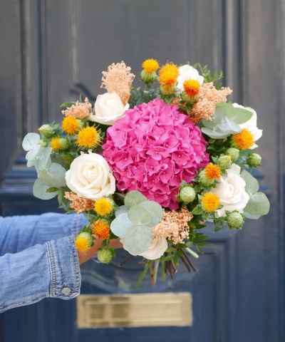 Ramo de flores colorido segurado em frente a uma porta azul escura