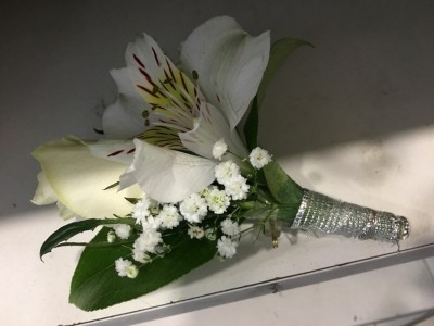 Buquê de flores brancas com fita prateada numa superfície clara