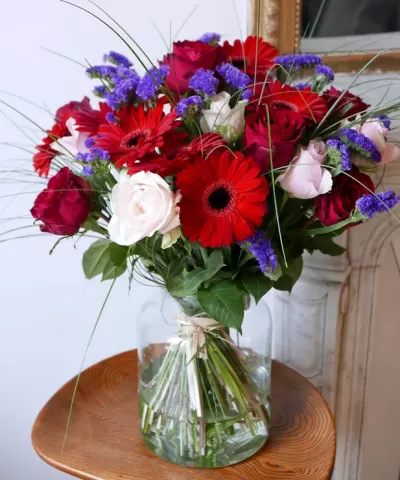 Arranjo floral colorido em jarro de vidro sobre mesa de madeira