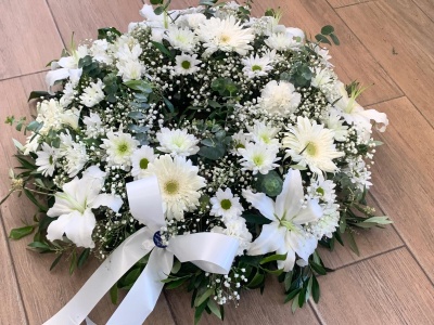 Prancha floral redonda com flores brancas e laço em chão de madeira clara