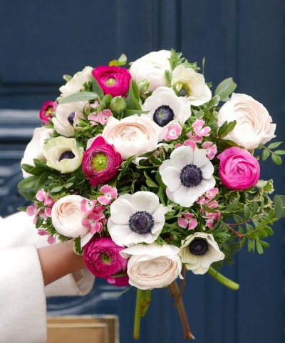 Buquê de flores com rosas brancas, anémonas e flores rosa choque, folhagem verde, fundo azul escuro