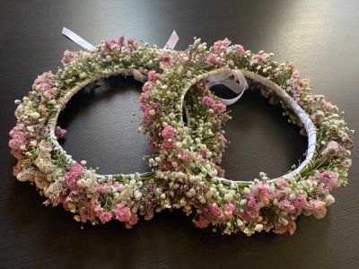 Duas coroas florais com flores brancas e cor-de-rosa sobre superfície preta