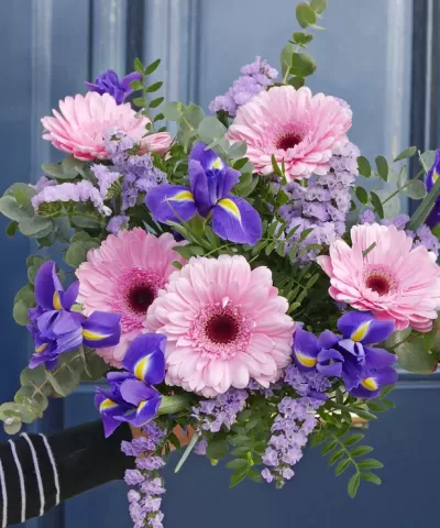 Bouquet colorido com flores cor-de-rosa, roxas e lilases em fundo azul