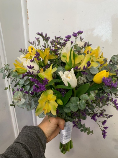 Ramo de flores amarelas, brancas e roxas com folhas verdes e eucalipto