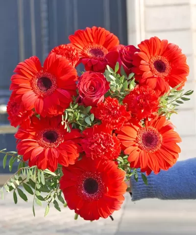 Ramo de flores vermelhas variadas com folhas verdes