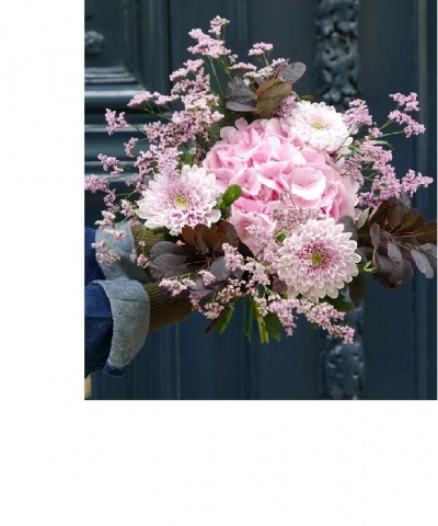 Ramo de flores rosa segurado por mão com manga azul junto a porta azul escura