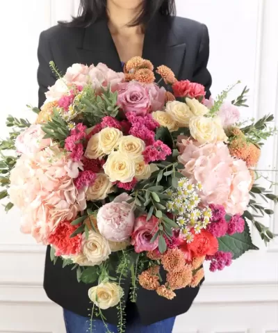 Bouquet colorido de flores variadas segurado por pessoa com blazer preto