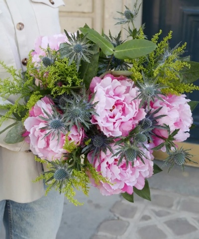 Ramo de peónias cor-de-rosa com folhas verdes e flores amarelas e azuis